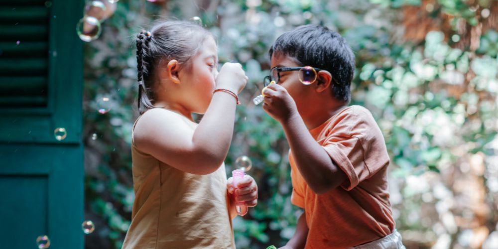 Bambini di diverse nazionalità che stanno giocando con le bolle di sapone esprimendo come Credem offre il suo supporto alla collettività