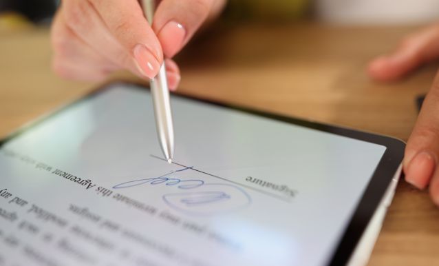 Una persona scrive su un tablet con una penna per firmare