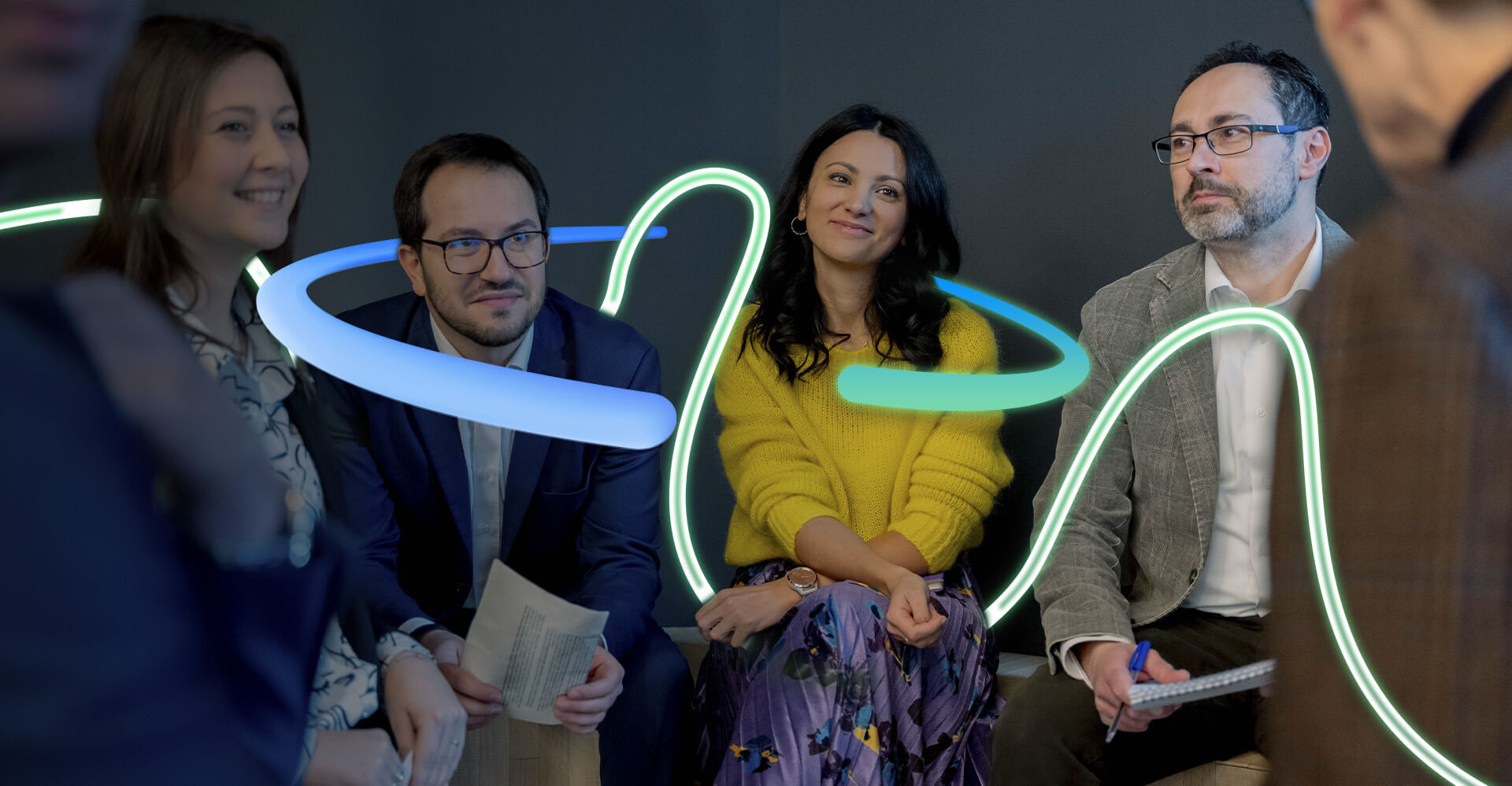 Colleghi Credem che si stanno consultando in maniera serena il tutto contornato da una grafica a forme irregolari che sta a rappresentare l’energia positiva presente nell’ufficio 