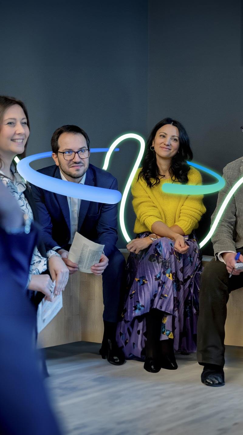 Colleghi Credem che si stanno consultando in maniera serena il tutto contornato da una grafica a forme irregolari che sta a rappresentare l’energia positiva presente nell’ufficio 