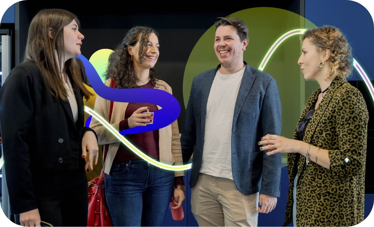 Quattro colleghi Credem che stanno sorridendo, contornati da una grafica a forme irregolari che sta a rappresentare l’energia positiva presente nell’ufficio.