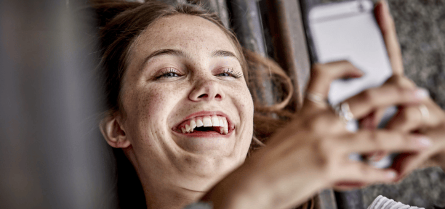 ragazza sorridente mentre guarda il suo cellulare