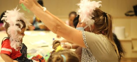 Maestra d’asilo e un bambino che giocano con le piume, esprime un’iniziativa Credem per dare un futuro ai bambini di tutto il mondo.
