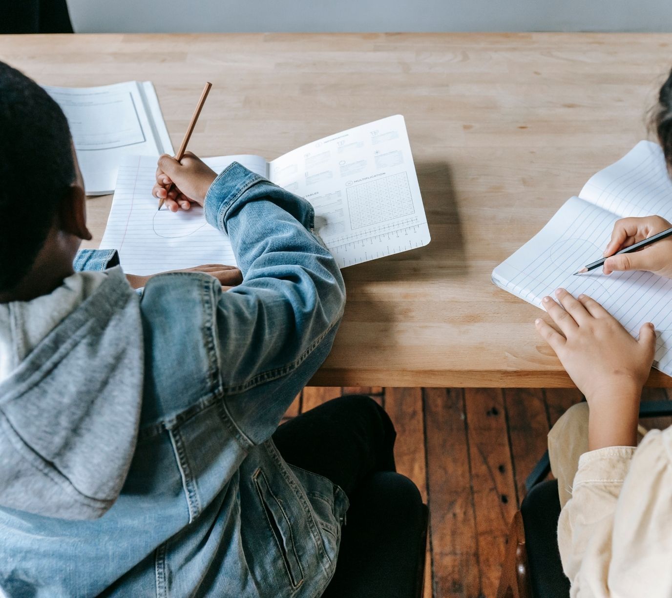 due bambini che scrivono su un quaderno seduti alla scrivania